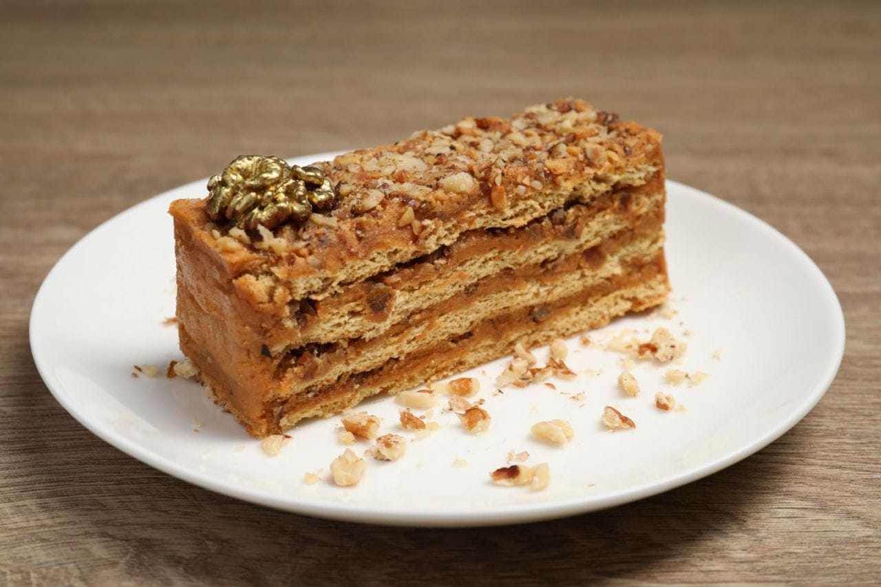 plate with delicious layered honey cake wooden table closeup